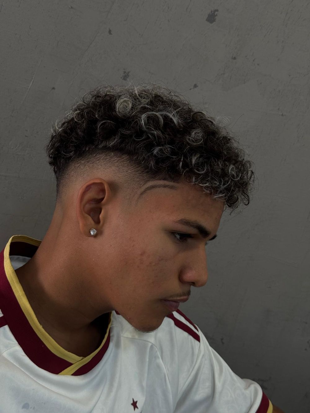 Fade com risco e cabelo cacheado com luzes